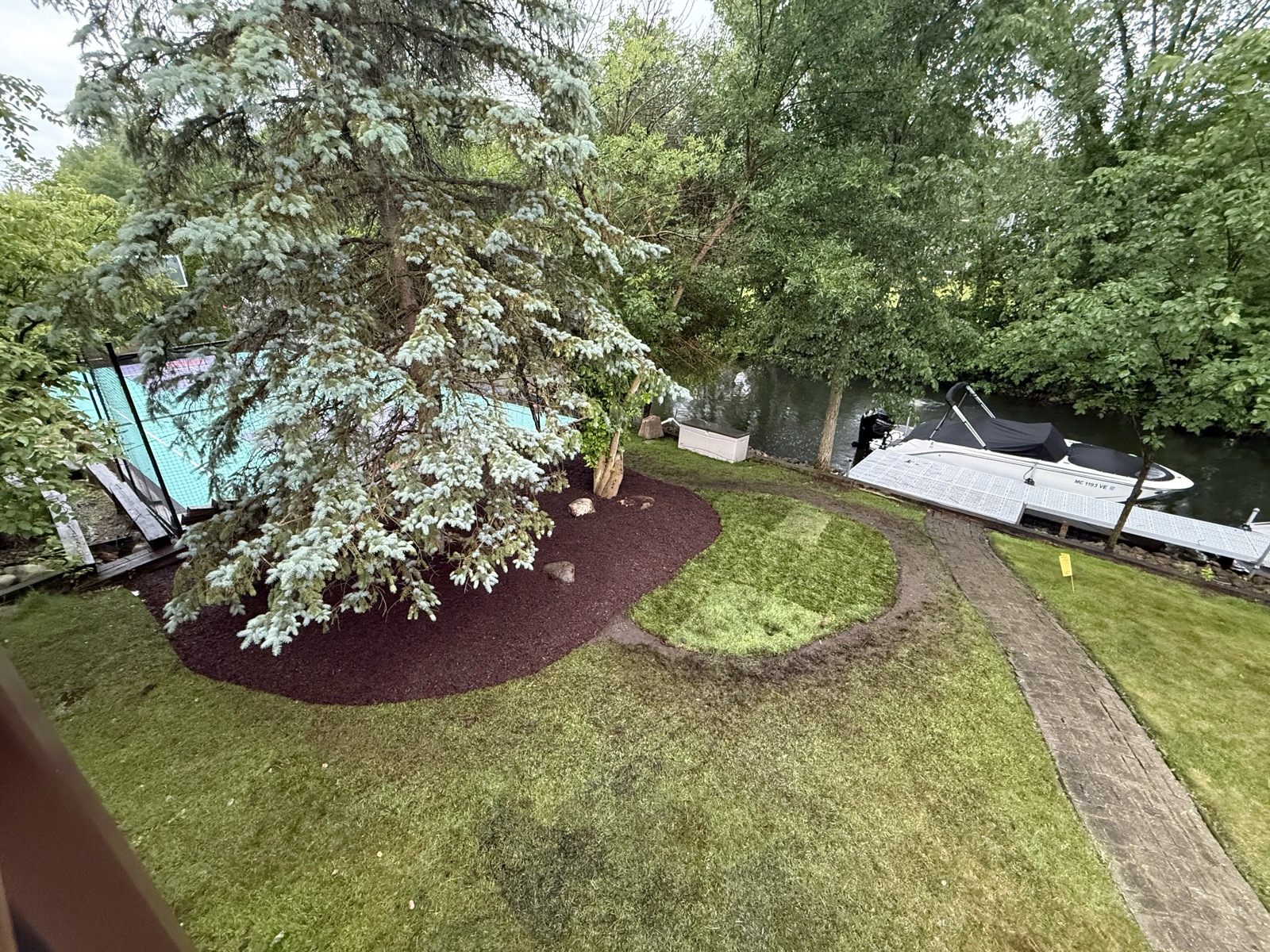 Same lakefront yard with beds cut, edged, and mulched